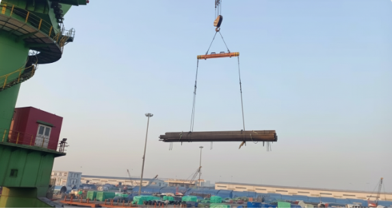 Crane lifting bundled materials across a storage and logistics yard