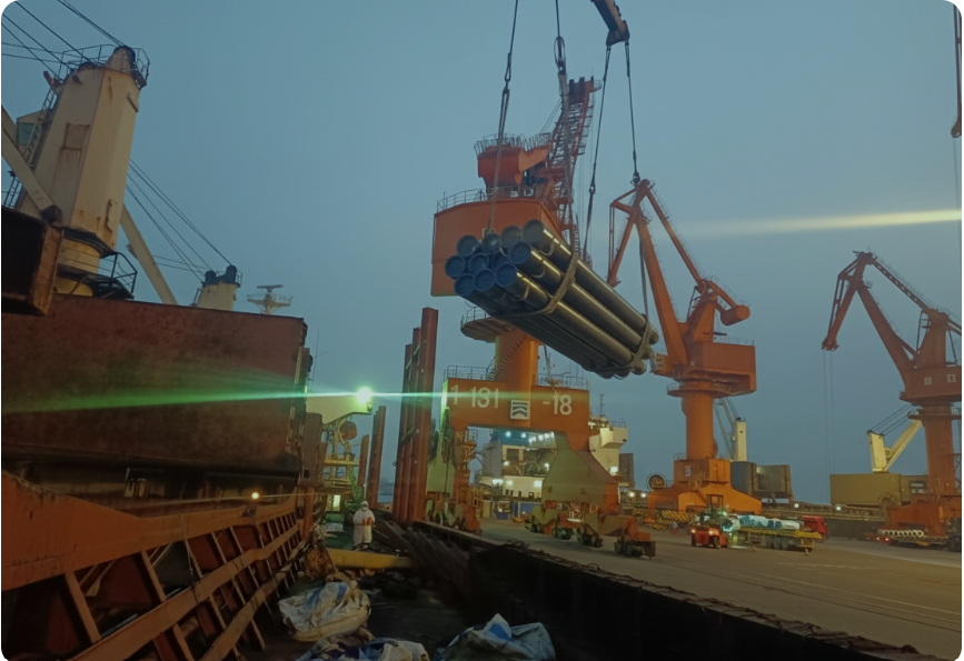 Crane loading bundled pipes onto a vessel at a commercial port